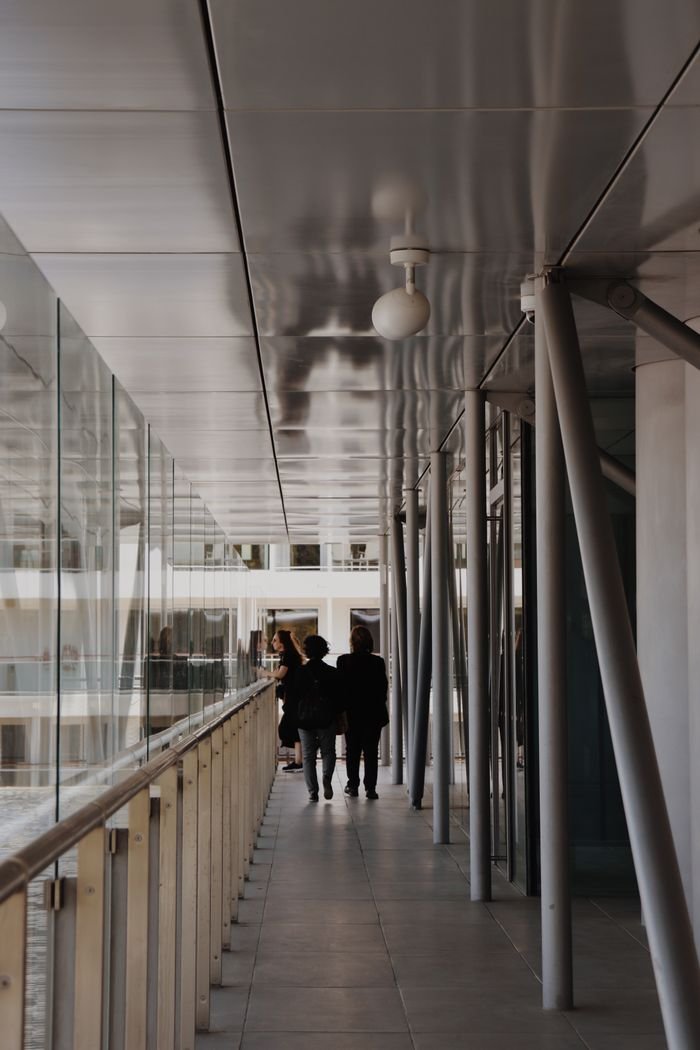 Modern urban walkway scene with people walking on a glass-lined path.